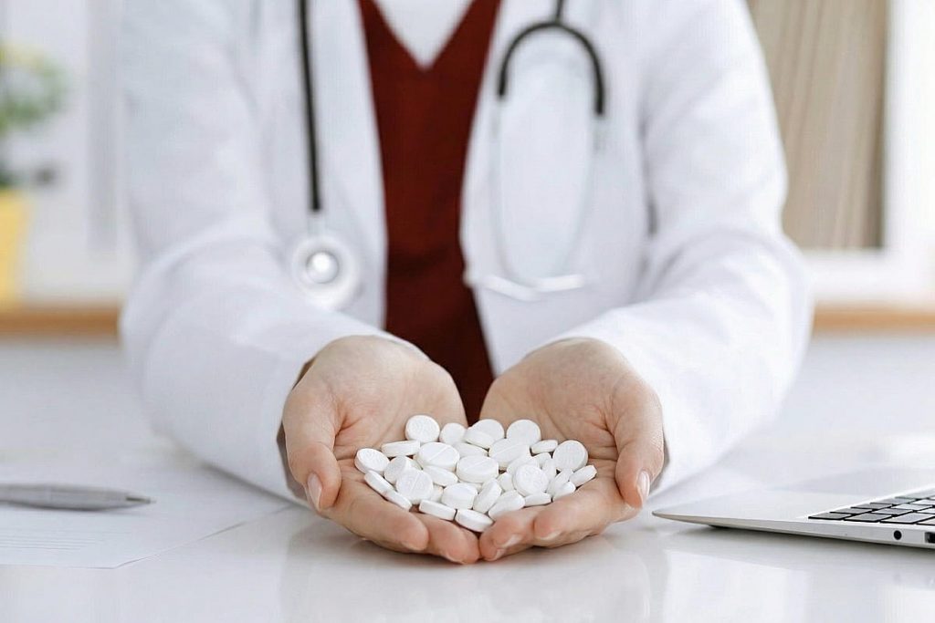 mujer con bata médica sosteniendo comprimidos de magnesio en las manos