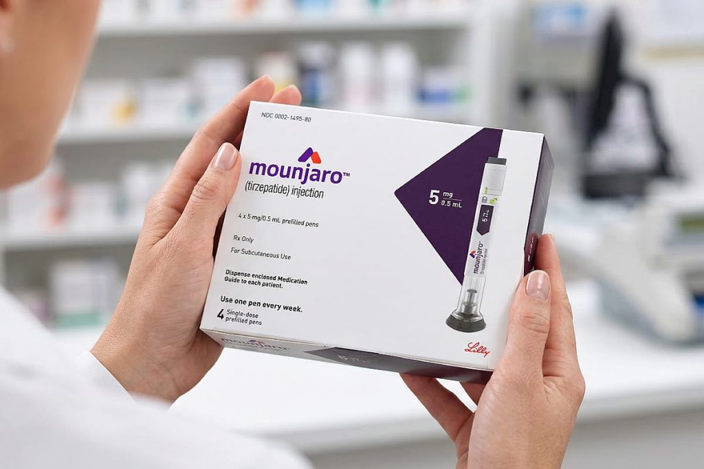 Caja de Mounjaro 5 mg con plumas precargadas de tirzepatida sostenida por manos en entorno de farmacia